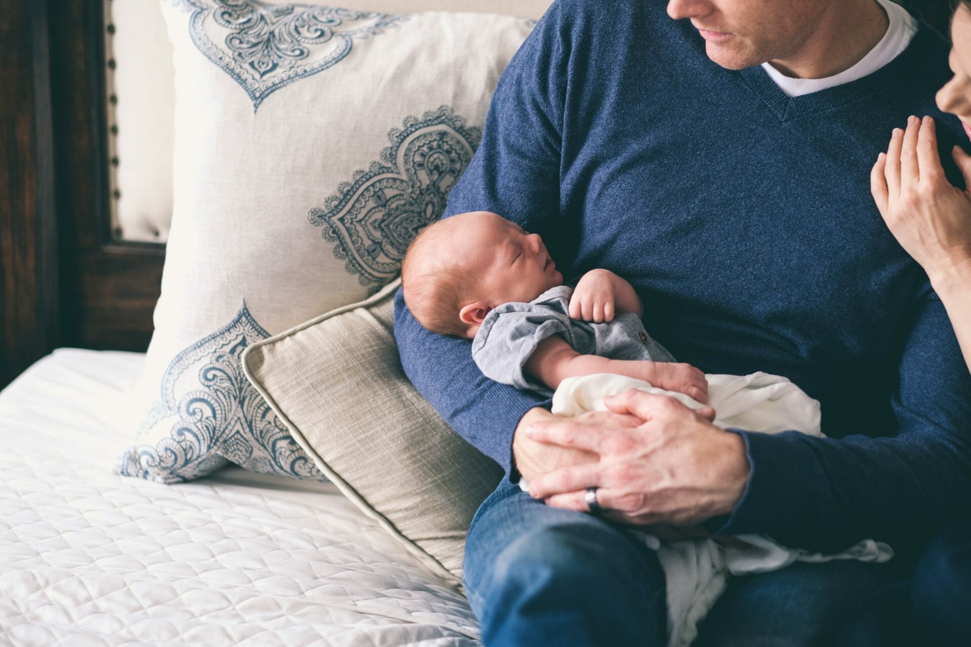 Man sitting on bed holding baby